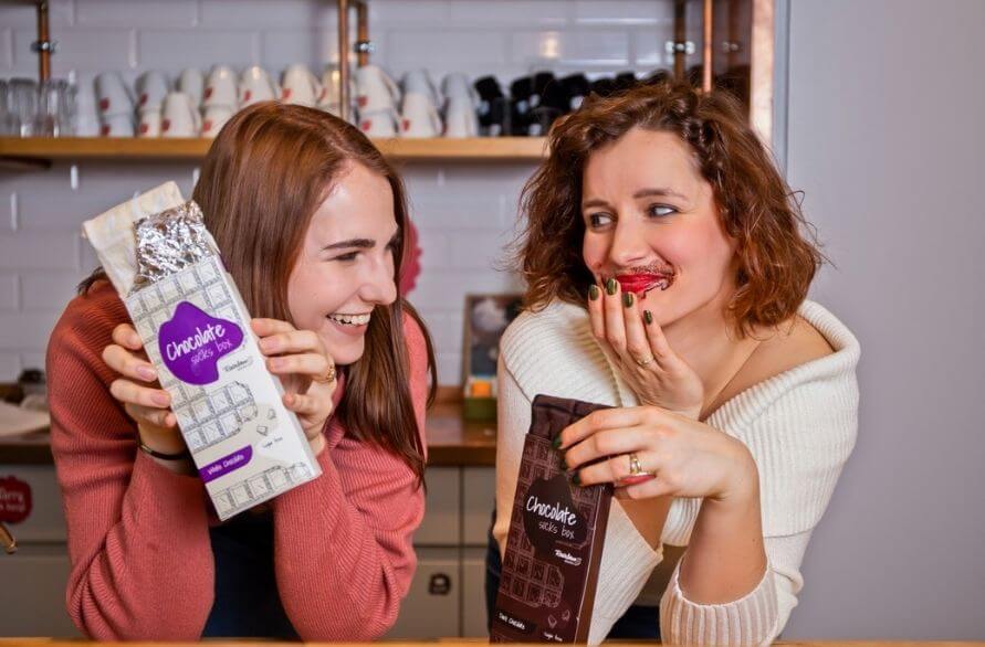 Women laughing and tasting white and milk chocolate in a socks’ version